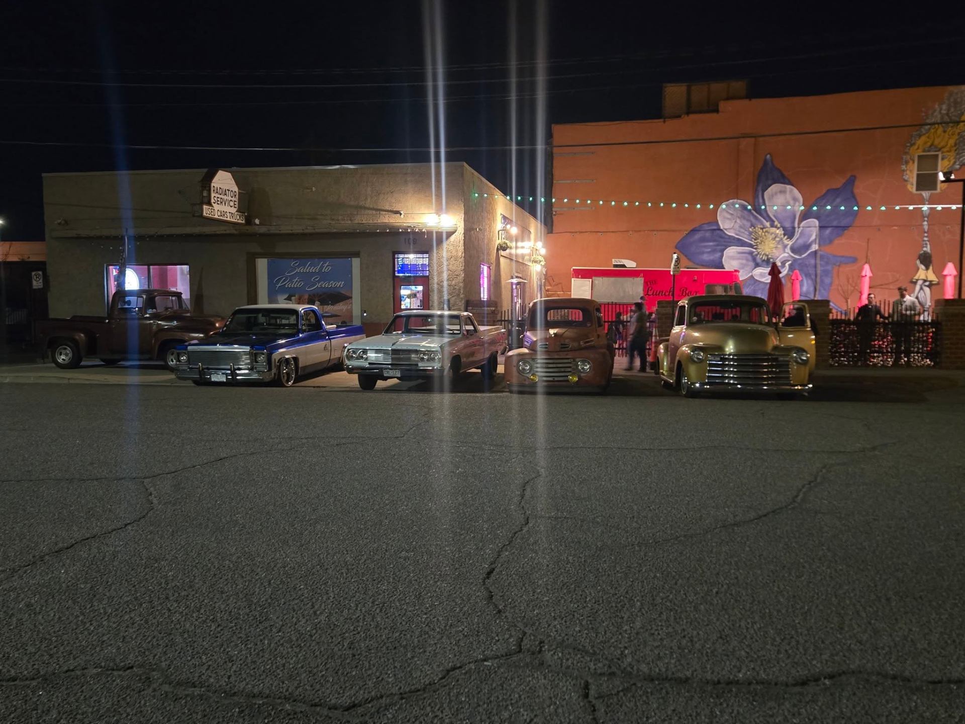 The Lunchbox at Presley's at night with classic lowrider trucks parked out front